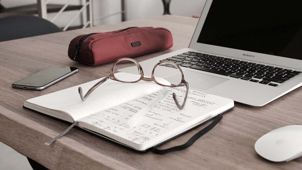 glasses and notebook with a laptop