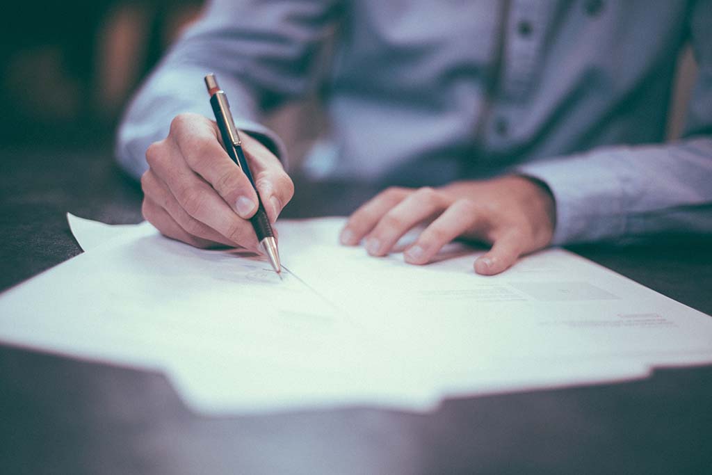 man writing with ink pen