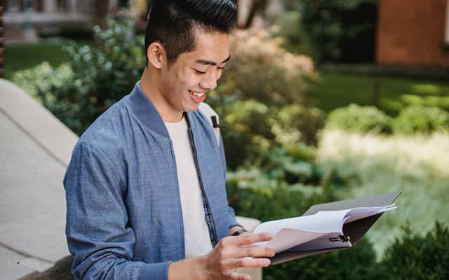 Man smiling while looking at a college course catalog